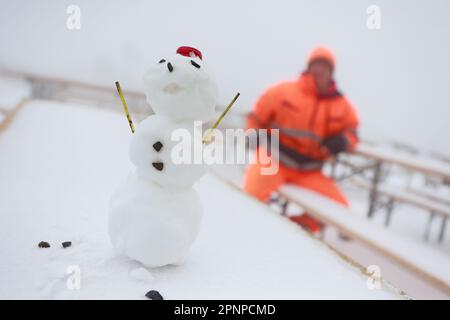 20. April 2023, Sachsen-Anhalt, Schierke: Ein Schneemann steht auf einem schneebedeckten Tisch eines Restaurants im Freien am Brocken. In der Nacht kehrte der Winter vorübergehend in die Harz-Berge zurück. In Gipfelbereichen gibt es eine geschlossene Schneeabdeckung. In den kommenden Tagen wird es immer wärmer sein. Foto: Matthias Bein/dpa Stockfoto