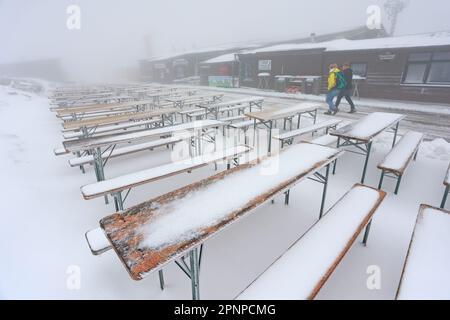 20. April 2023, Sachsen-Anhalt, Schierke: Die Tische und Bänke eines Restaurants im Freien am Brocken sind schneebedeckt. In der Nacht kehrte der Winter vorübergehend in die Harz-Berge zurück. In Gipfelbereichen gibt es eine geschlossene Schneeabdeckung. In den kommenden Tagen wird es immer wärmer sein. Foto: Matthias Bein/dpa Stockfoto