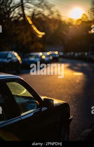 Eine malerische Aufnahme einer Straße mit verschiedenen Fahrzeugen, die die Straße hinunterfahren, während die Sonne im Hintergrund untergeht Stockfoto