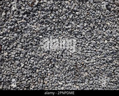 Hintergrund mit grauer Kieselsteinstruktur. Struktur aus gebrochenem Stein oder zerkleinertem Gestein mit Platz für Text. Dunkler Hintergrund von zerkleinertem Granitkies, nahe Stockfoto