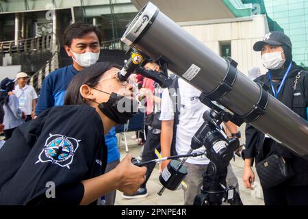 Ein Mann sieht am 20. April 2023 in Jakarta, Indonesien, eine hybride partielle Sonnenfinsternis mit Teleskop. Die hybride Sonnenfinsternis ist eine einzigartige Art von Sonnenfinsternis, die zwei Phasen gleichzeitig erlebt. (Foto: Ahmad Rajif Sidiq/INA Photo Agency/Sipa USA) Stockfoto