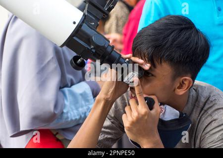 Ein Kind sieht am 20. April 2023 in Jakarta, Indonesien, eine hybride partielle Sonnenfinsternis mit Teleskop. Die hybride Sonnenfinsternis ist eine einzigartige Art von Sonnenfinsternis, die zwei Phasen gleichzeitig erlebt. (Foto: Ahmad Rajif Sidiq/INA Photo Agency/Sipa USA) Stockfoto