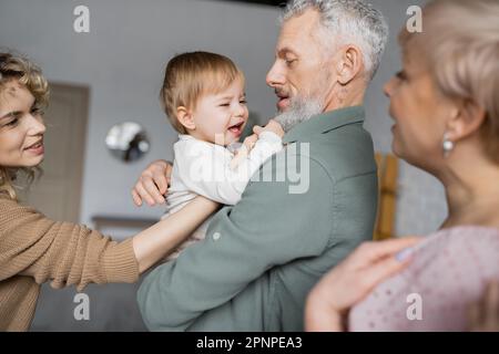 Unzufriedenes Mädchen, das zu Hause in den Händen des bärtigen Großvaters weint, Börsenbild Stockfoto