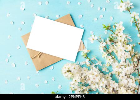 Leere Hochzeitsgrußkarte oder Einladung mit blühenden Kirschblüten auf pastellblauem Hintergrund. Modell. Flach verlegt Stockfoto