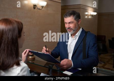 Ein Mann kam ins Hotel und unterschrieb das Dokument Stockfoto