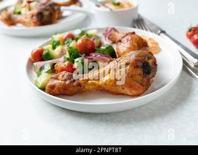 Kohlenhydratarmes Abendessen mit im Ofen gebackenem Hähnchen, mariniertem Salat und Paprika Feta Käsedip auf einem Teller Stockfoto