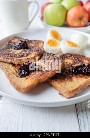 French Toast mit Blaubeermarmelade und gekochten Eiern auf einem Teller zum Frühstück Stockfoto