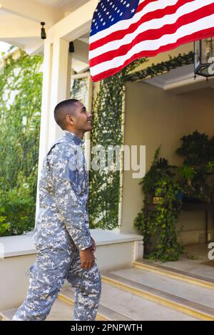 Ein glücklicher amerikanischer Soldat, der eine Militäruniform trägt und vor dem Haus steht Stockfoto