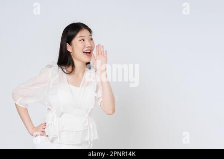 Porträt einer jungen Frau mit offenem Mund, die sich die Hände hebt und schreiende Durchsage auf weißem Hintergrund isoliert. Stockfoto