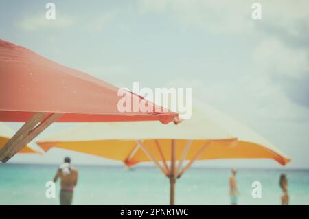 Zwei Sonnenschirme am Strand mit drei Personen in der Ferne, Jamaika Stockfoto