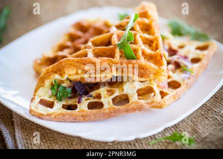 Eieromelette gefüllt mit Zwiebeln und Kräutern, gebraten in Form von Waffeln, auf einem Holztisch Stockfoto