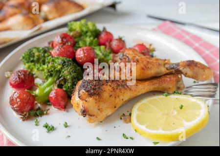 Gesunde kohlenhydratarme Mahlzeit zum Abendessen oder Mittagessen mit gebackenen Hähnchenschenkeln und mariniertem Brokkoli, Rettichsalat Stockfoto