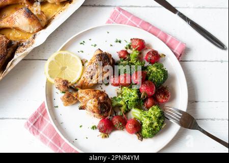 Kohlenhydratarmes Abendessen mit gebackenem Hähnchen und warmem Rotrettich, Brokkoli-Salat auf einem Teller Stockfoto