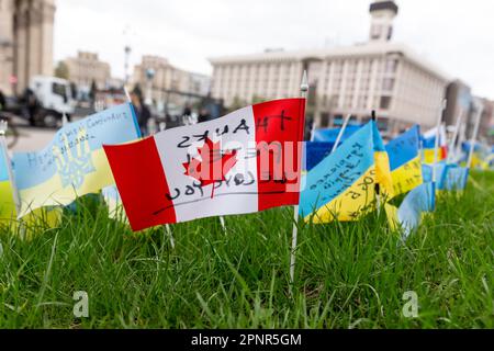 Kiew, Ukraine. 20. April 2023. Die kanadische Flagge ist zwischen blauen und gelben ukrainischen Nationalflaggen mit Namen gefallener Soldaten auf dem Maidan Nezalezhnosti (Unabhängigkeitsplatz) im Zentrum von Kiew, der Hauptstadt der Ukraine am 20. April 2023, zu sehen. Familien und Freunde des getöteten Soldaten hinterlassen die Flaggen als Gedenkstätte für ihre Lieben. Während sich die Invasion der Ukraine durch die russischen Streitkräfte in vollem Umfang auf eine Gegenoffensive vorbereitet. (Foto: Dominika Zarzycka/Sipa USA) Guthaben: SIPA USA/Alamy Live News Stockfoto