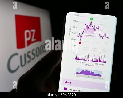 Person, die ein Mobiltelefon mit einer Webseite des britischen Konsumgüterunternehmens PZ Cussons plc auf dem Bildschirm mit Logo hält. Konzentrieren Sie sich auf die Mitte des Telefondisplays. Stockfoto