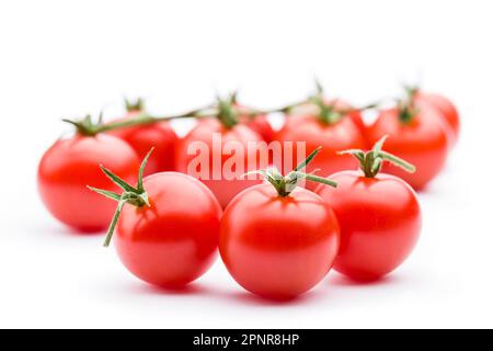 Kleine rote Kirschtomaten auf weißem Hintergrund. Stockfoto