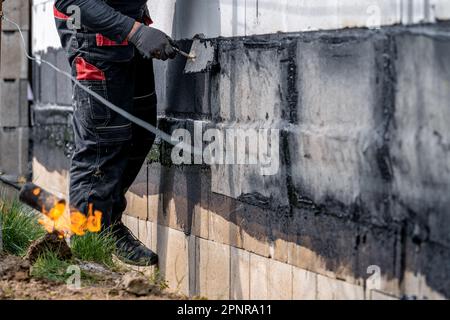 Abdichtung der Wand mit einem überzogenen Asphaltband während des Hausbaus Stockfoto