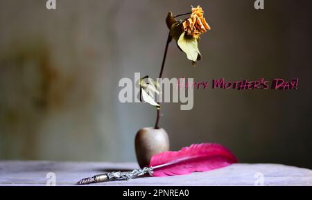 Gelbe Blume in einer kleinen Vase und ein roter Stift zum Muttertag Stockfoto