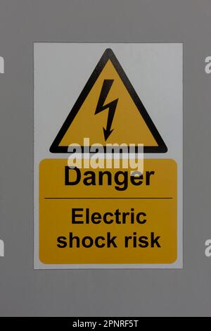 Warnschild „Gefahr eines elektrischen Schlags“ auf grauem Hintergrund Stockfoto