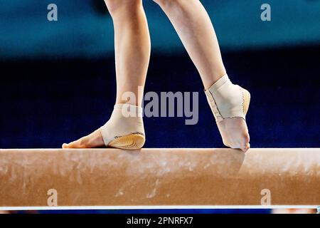 Nahaufnahme der Beine weibliche Turnerin auf Balancestrahl in Gymnastik, angepasste Neopren-Knöchelstütze mit Fersenschale Stockfoto