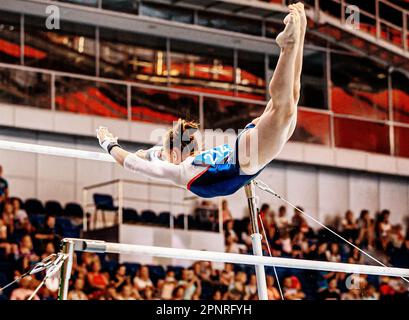 Flugelement von der niedrigen bis zur hohen Turngymnastik an unebenen Bars in der künstlerischen Gymnastik Stockfoto