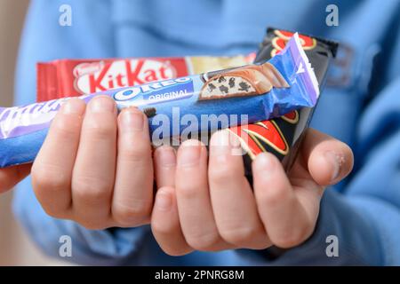 Arahal. Sevilla. Spanien. 18. März 2023. Hände eines Kindes mit Schokolade verschiedener Marken. Ein übermäßiger Zuckerkonsum kann negative CO-Emissionen zur Folge haben Stockfoto