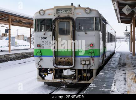 Ein ein-Mann-Zug der JR Hokkaido KIHA 40-Serie an einem verschneiten Tag am Bahnhof Oshamambe (oder Oshamanbe) in Japan. Stockfoto