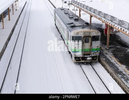 Ein ein-Mann-Zug der JR Hokkaido KIHA 40-Serie an einem verschneiten Tag am Bahnhof Oshamambe (oder Oshamanbe) in Japan. Stockfoto