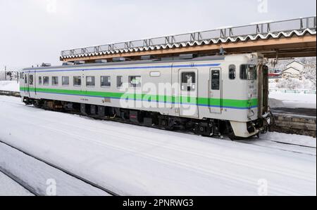 Ein Zug der JR Hokkaido KIHA 40-Serie an einem verschneiten Tag am Bahnhof Oshamambe (oder Oshamanbe) in Japan. Stockfoto