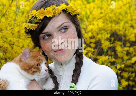 Nahaufnahme eines glücklichen Sommersprossen-Mädchens und einer roten Katze im Frühlingspark Stockfoto