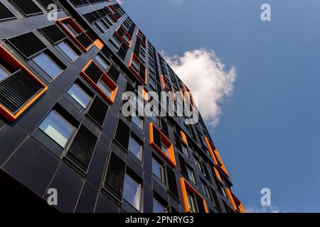 Modernes schwarz-orangefarbenes Gebäude vor einem blauen Himmel, mit Blick nach oben. Stockfoto