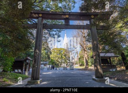 Ein großes hölzernes Torii-Tor, das das NTT Docomo Yoyogi Building am Nordeingang des Meiji-Schreins (oder Meiji Jingu) in Tokio, Japan, umrahmt. Stockfoto