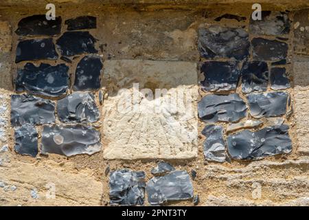 Die Überreste einer zerkratzten Sonnenuhr auf einem mit Feuerstein umrahmten Hintern in St. Mary, der Jungfrauenkirche, Parham, Suffolk Stockfoto