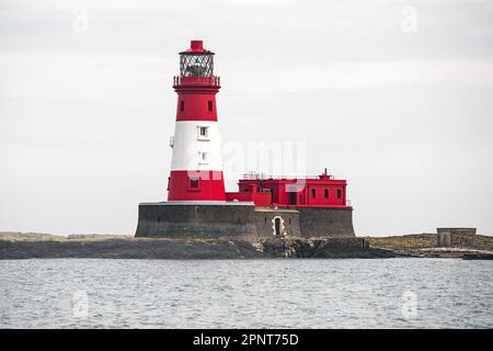 Ein imposanter weiß-roter Leuchtturm steht hoch vor einem klaren Himmel, der ikonische Turm reicht in Richtung Himmel Stockfoto