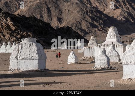 Frauen laufen unter den Chortens in Mane, Shey, Ladakh, Indien Stockfoto