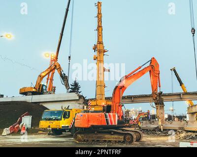 Bau einer gebrochenen Brücke an einer verkehrsreichen Straße. Der Häcksler macht ein Loch in den Asphalt, um ihn zu ersetzen. Reparatur der Brücke hinter der Barriere für die Stockfoto