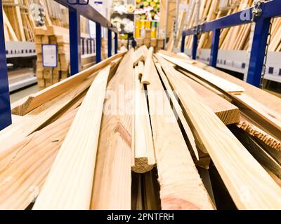 Holzbraun gesägte natürliche Bauplatten kleben Baumstämme mit Knoten auf einem Regal auf einem Sägewerk im Geschäft. Der Hintergrund. Stockfoto