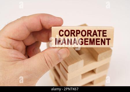 Geschäftskonzept. Ein Mann hält in seinen Händen einen Holzblock mit der Aufschrift "Corporate Management" Stockfoto