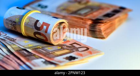 Konzept von vielen Euro: Ein Stapel gerollter 50-Euro-Scheine, die auf weißem Hintergrund liegen und Tausende von Euro in 50-Euro-Scheinen darstellen Stockfoto