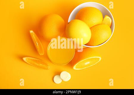 Glas Vitamin-C-Brausetablette, gelöst in Wasser und Früchten auf orangefarbenem Hintergrund Stockfoto