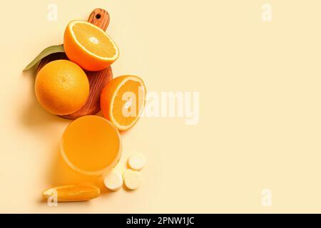Brett mit Glas Vitamin-C-Brausetablette, gelöst in Wasser und Orangen auf beigefarbenem Hintergrund Stockfoto