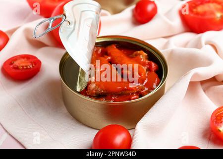 Geöffnete Dose mit Fisch in Sauce und Tomaten auf Serviette Stockfoto