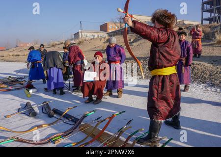 Chinbat Gonchigjamts, richtig, richtet einen Bogen während eines Provinzturniers in Uriankhai, einer von drei Arten traditioneller mongolischer Bogenschießen, auf einen gefrorenen Fluss in Murun, Provinz Khuvsgul, Mongolei am 9. Januar 2022. In diesem Wettbewerb, der zur Förderung des Nationalsports und zur Vorbereitung des Naadam-Festivals im Sommer veranstaltet wird, beurteilen Bogenschützen die Leistungen des jeweils anderen. (Dolgormaa Sandagdorj/Global Press Journal) Stockfoto