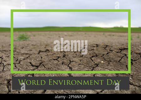 Ein gerissener Boden mit einem grünen Feld im Hintergrund. Dürrewasser und Klimakrise.Weltumwelttag am 5. juni Stockfoto