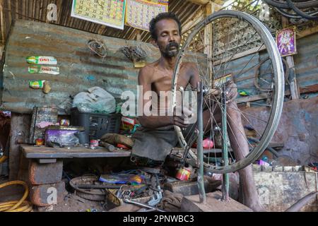 Kanthaiya Murukananthan repariert am 8. Juli 2022 in seinem Geschäft in Mudaliyarkulam, Sri Lanka, einen Fahrradreifen. Das Radfahren hat aufgrund einer massiven Kraftstoffknappheit im Land zugenommen, und viele haben sich entschieden, alte Fahrräder zu reparieren, da der Preis für Fahrräder gestiegen ist. Murukananthan sagt, es sei das erste Mal, dass er Tag und Nacht in seinen 15 Jahren Berufserfahrung arbeitet. (Thayalini Indrakularasa/Global Press Journal) Stockfoto