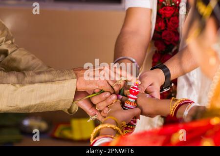 Hinduistisches Hochzeitsritual während der Hochzeit, bei dem Familienälteste die Verbindung zwischen Braut und Bräutigam besiegeln, indem sie sie in der Hand halten. Dieses Ritual heißt s Stockfoto