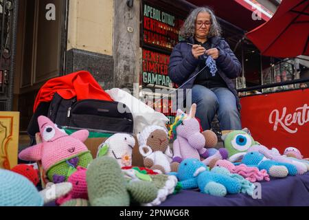 Silvina Celorrio häkert am 19. August 2022 einen Tintenfisch auf der Straße in Buenos Aires, Argentinien. Celorrio, der seit dem Verlust ihres Arbeitsplatzes im Jahr 2017 Amigurumi verkauft hat, sagt, dass die Umsatzerlöse aufgrund der Inflation und der Finanzkrise des Landes zurückgegangen seien. (Lucila Pellettieri/Global Press Journal) Stockfoto