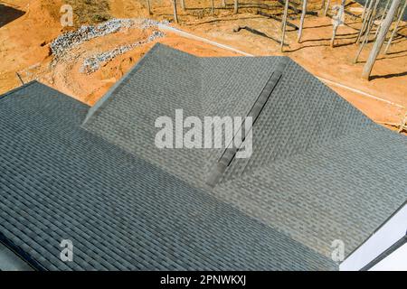 Sobald Asphaltschindeln installiert sind, die die Qualität der Dacharbeiten des neuen Hauses abdecken, wird eine Inspektion durchgeführt Stockfoto