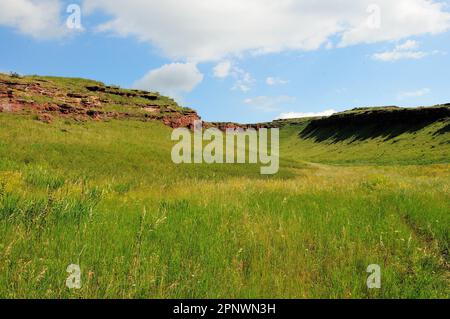 Blick vom Grund der Höhle auf die sanften Hänge des Hügels mit den Überresten der zerstörten Mauern des antiken Heiligtums in einem klaren Sommer Stockfoto