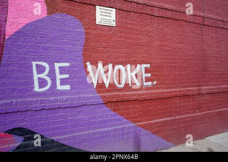 "Wach sein" -Schild an einer Ziegelwand Stockfoto